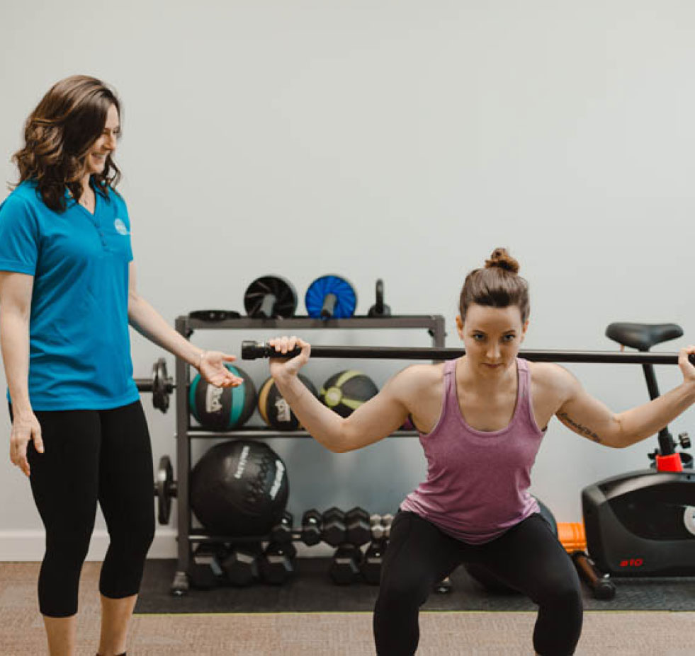 Katy guiding a client through a strength exercise